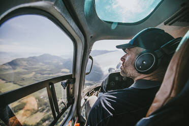 Ein freiwilliger Such- und Rettungshelfer schaut aus dem Fenster eines Hubschraubers - CAVF65746