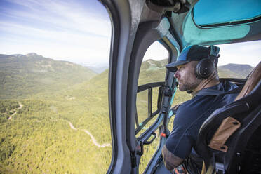 Passagier schaut aus dem Fenster eines Hubschraubers - CAVF65754