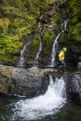 Mann geht beim Canyoning über einen kleinen Wasserfall. - CAVF65769