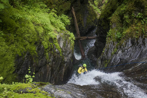 Hochformatige Ansicht eines Mannes, der sich an einem Wasserfall abseilt. - CAVF65782