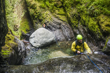 Man smiles while rappelling over the edge of a waterfall. - CAVF65789