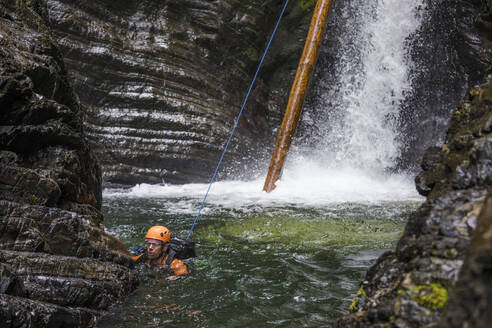 Mann schwimmt nach Abseilen in Wasserfall in Sicherheit. - CAVF65793