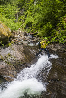 Ein Wanderer tritt über einen kleinen Wasserfall im unteren Teil des Frost Creek. - CAVF65797