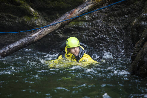 Mann schwimmt durch einen Pool, nachdem er sich in einer Flussschlucht abgeseilt hat - CAVF65805