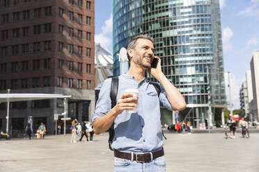 Lächelnder Geschäftsmann beim Telefonieren in der Stadt, Berlin, Deutschland - WPEF02064