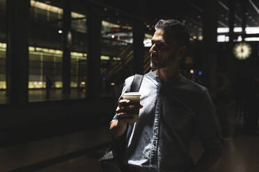 Mann mit Kaffee zum Mitnehmen auf dem Bahnhof im Schatten, Berlin, Deutschland - WPEF02073