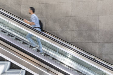 Businessman in a hurry walking up escalator in the city, Berlin, Germany - WPEF02077