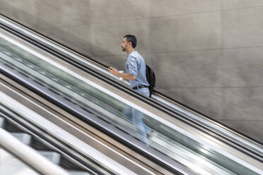 Geschäftsmann geht Rolltreppe in der Stadt hinauf, Berlin, Deutschland - WPEF02078