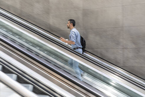 Geschäftsmann geht Rolltreppe in der Stadt hinauf, Berlin, Deutschland - WPEF02078