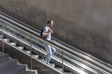 Businessman walking down escalator in the city, Berlin, Germany - WPEF02079