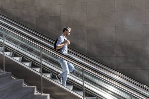 Geschäftsmann geht Rolltreppe in der Stadt hinunter, Berlin, Deutschland - WPEF02079