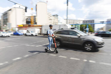 Geschäftsmann fährt E-Scooter auf der Straße in der Stadt, Berlin, Deutschland - WPEF02080