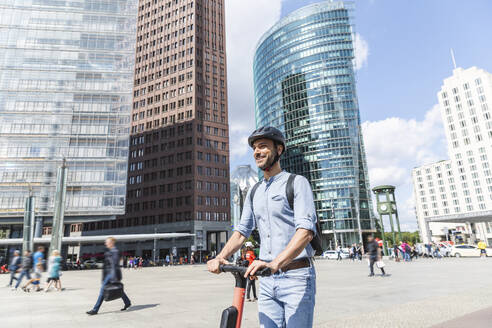 Geschäftsmann mit E-Scooter auf dem Marktplatz, Berlin, Deutschland - WPEF02085