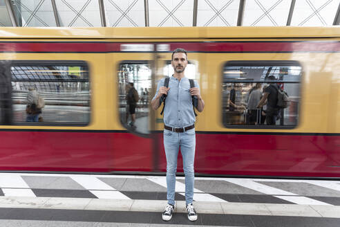 Porträt eines Mannes auf dem Bahnsteig mit einem Zug im Hintergrund, Berlin, Deutschland - WPEF02100