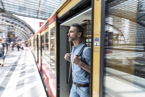 Mann beim Aussteigen aus dem Zug am Bahnsteig, Berlin, Deutschland - WPEF02102