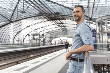 Lächelnder Mann auf dem Bahnhof, der auf den Zug wartet, Berlin, Deutschland - WPEF02103