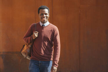 Porträt eines lächelnden jungen Mannes, der eine Tasche trägt - VPIF01604