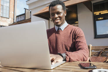 Young man using laptop in a coffee shop - VPIF01610