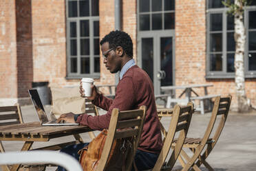 Junger Mann mit Laptop in einem Café, trinkt Kaffee - VPIF01618