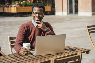 Junger Mann mit Laptop in einem Café, trinkt Kaffee - VPIF01624