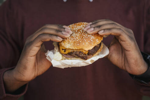 Close-up of hands, holding cheeseburger - VPIF01632