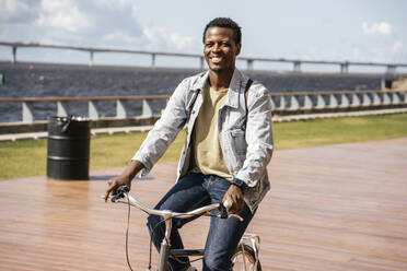 Junger Mann fährt Fahrrad am Meer - VPIF01683