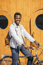 Junger Mann auf dem Fahrrad vor einer Holztür - VPIF01689