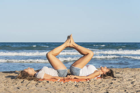 Zwei Frauen praktizieren Acro Yoga am Strand - DLTSF00257