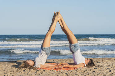 Zwei Frauen praktizieren Acro Yoga am Strand - DLTSF00259