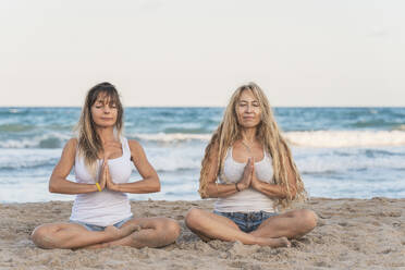 Zwei Frauen üben Acro Yoga am Strand und meditieren - DLTSF00266