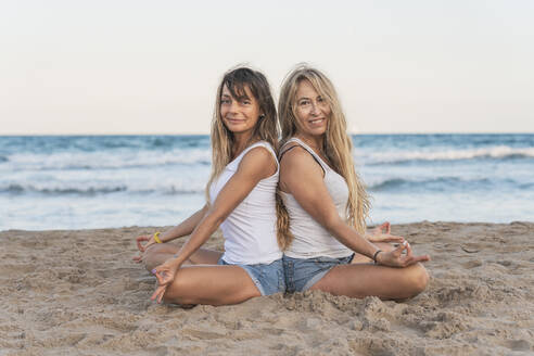 Zwei Frauen praktizieren Acro Yoga am Strand - DLTSF00268