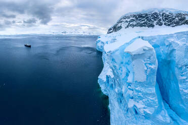 Luftaufnahme eines wissenschaftlichen Schiffs, das in der Nähe eines Eisbergs in der Antarktis fährt - AAEF05037