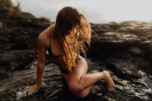 Frau posiert auf Felsen am Meer, Princeville, Hawaii, USA - ISF22509