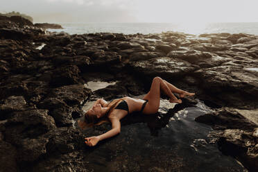 Frau liegt auf Felsen am Meer, Princeville, Hawaii, USA - ISF22510