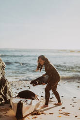 Frau legt Schwimmflossen in Kajak am Strand, Big Sur, Kalifornien, Vereinigte Staaten - ISF22664