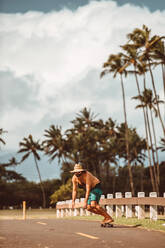 Mittlerer Erwachsener, männlicher Skateboarder mit Strohhut auf einer Landstraße, Haiku, Hawaii, USA - ISF22695