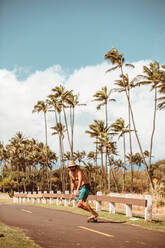 Mittlerer Erwachsener, männlicher Skateboarder mit Strohhut auf einer Landstraße, Haiku, Hawaii, USA - ISF22697