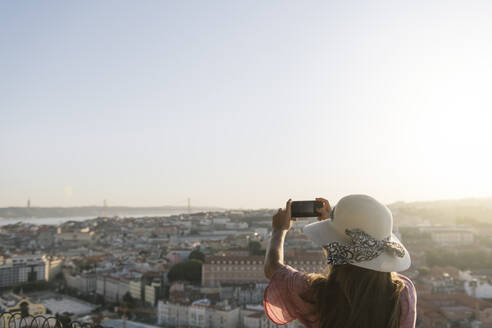 Frau, die ein Smartphone-Foto vom Stadtpanorama macht, Lissabon, Portugal - AHSF01006