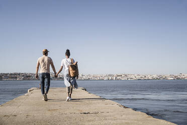 Young couple walking on pier at the waterfront, Lisbon, Portugal - UUF19084