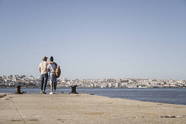 Junges Paar steht auf dem Pier am Wasser, Lissabon, Portugal - UUF19085