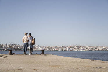 Young couple standing on pier at the waterfront, Lisbon, Portugal - UUF19085