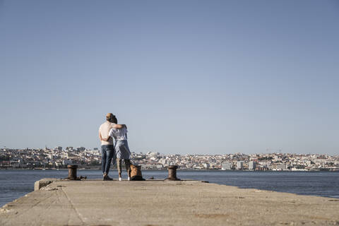 Junges Paar steht auf dem Pier am Wasser, Lissabon, Portugal, lizenzfreies Stockfoto