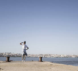 Junge Frau steht auf dem Pier am Wasser, Lissabon, Portugal - UUF19089