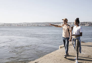 Junges Paar, das auf dem Pier am Wasser spazieren geht, Lissabon, Portugal - UUF19098