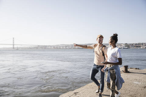 Junges Paar, das auf dem Pier am Wasser spazieren geht, Lissabon, Portugal, lizenzfreies Stockfoto