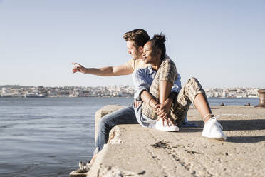 Junges Paar sitzt am Pier am Wasser, Lissabon, Portugal - UUF19119