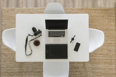 Weißer Tisch mit Kamera, Laptop, Smartphone, Tasse Kaffee und Grafiktablett, Draufsicht - AHSF01016