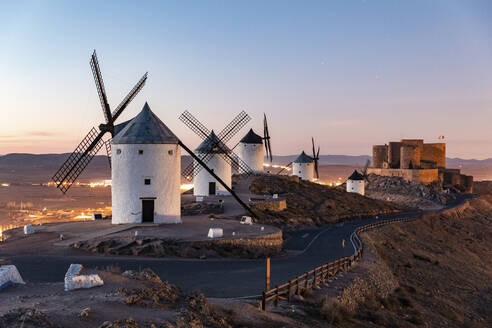 Spanien, Provinz Toledo, Consuegra, Straße entlang einer Reihe von alten Windmühlen auf einem Hügel - WPEF02111