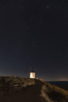 Spain, Province of Toledo, Consuegra, Starry sky over old windmill standing on top of hill at night - WPEF02113