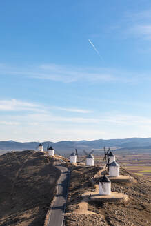 Spain, Province of Toledo, Consuegra, Country road along row of old windmills standing on top of hill - WPEF02131